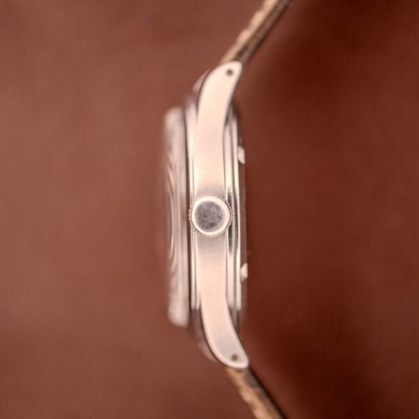 Side view of Omega WWII Era Military "US ARMY" Ref. 2179 stainless steel case with crown, featuring Cal. 30T2 SC movement, set against a blurred brown background.