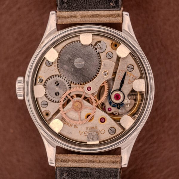 Close-up of the Omega WWII Era Military "US ARMY" Ref. 2179 in stainless steel, showcasing its exposed Cal. 30T2 SC mechanical movement and gears, paired with a black leather strap.