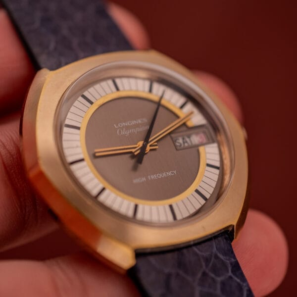 Close-up of a vintage gold Longines Olympian High Frequency Ref. 3141 Cal. 6972 wristwatch, displaying SAM for the day and 31 for the date, celebrated for its precise high frequency movement.