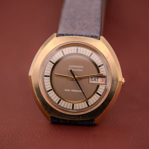 Gold Longines Olympian High Frequency Ref. 3141 watch, Cal. 6972, featuring a blue strap and displaying SAT 31 on its brown dial.