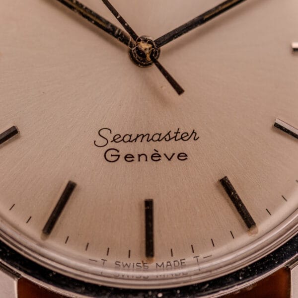 Close-up of Omega Automatic Seamaster Geneve Double Signed Dial Ref. 165.002 watch face with black hour markers and hands.