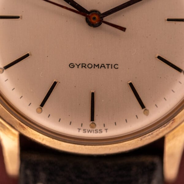 Close-up of a Girard Perregaux Gyromatic wristwatch with a 10k gold filled case and cream dial.