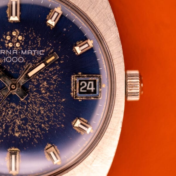 Close-up of the Eterna Matic 1000 Blue Patina Dial 110T, featuring a blue patina dial with date window set to 24 and striking stainless steel details, powered by Cal. 1489K.