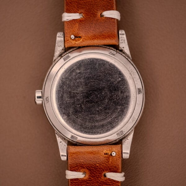 A close-up of the scratched back of an Omega Automatic Seamaster Bumper "Türler Dial" Ref. 2576 wristwatch with a brown leather strap.