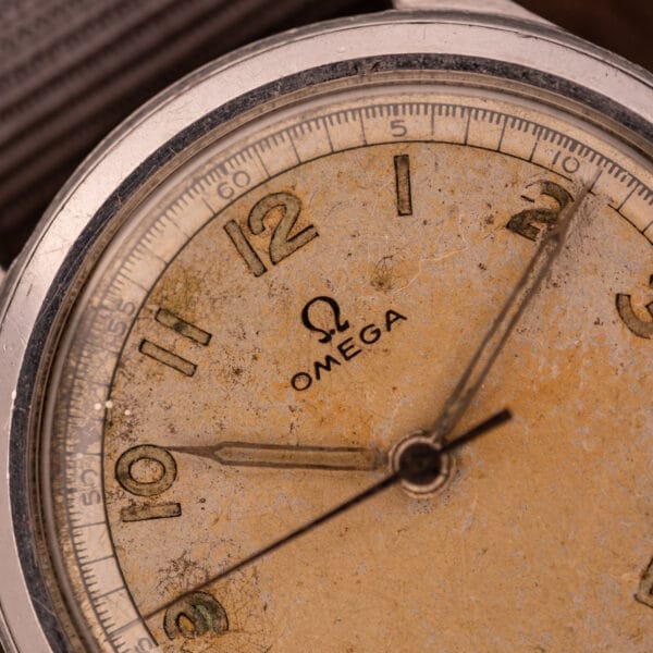 Close-up of a vintage Omega Patina Dial Military "US ARMY" Ref. 2179 watch, showing its worn, yellowed dial with visible scratches and featuring the Cal. 30T2 SC movement in a stainless steel case.