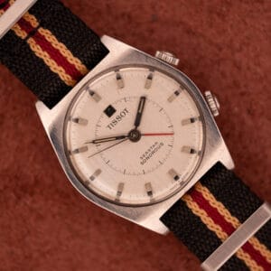 A Tissot Seastar Sonorous Alarm Watch in Stainless Steel Ref. 40500 with a striped fabric band, displayed on a textured brown surface.