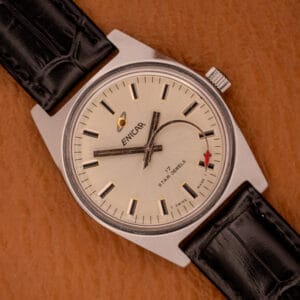 An Enciar Ocean Peal 17 Star Jewels "Space Ship Seconds" Ref. 2334 wristwatch with black leather strap is displayed elegantly on a brown textured surface.