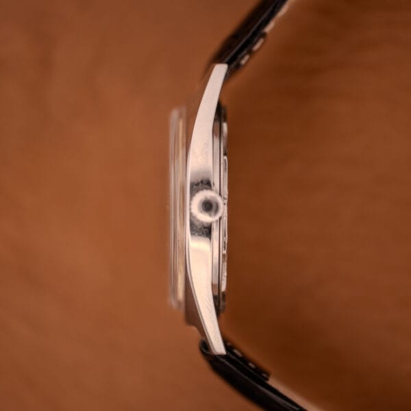 Side view of the Enciar Ocean Peal 17 Star Jewels "Space Ship Seconds" Ref. 2334, featuring a silver case, visible crown, and black leather strap on a brown background—an elegant classic design.