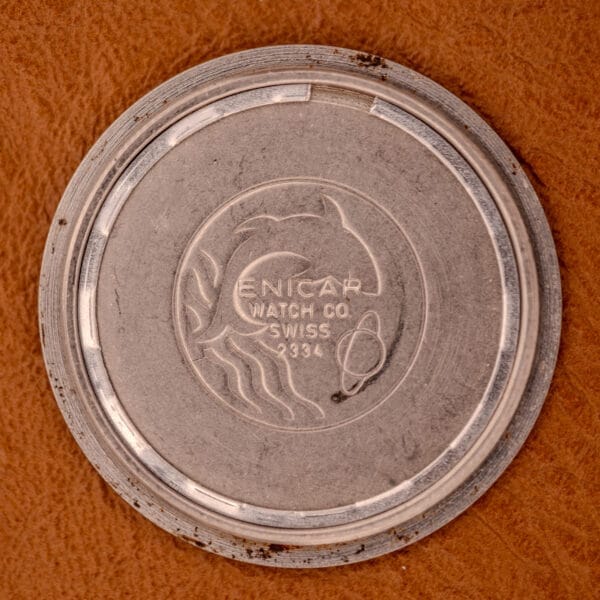 Enicar Ocean Pearl 17 Star Jewels "Space Ship Seconds" Ref. 2334 case back with dolphin and planet logo, engraved text, and Space Ship Seconds motif, shown on a brown surface.