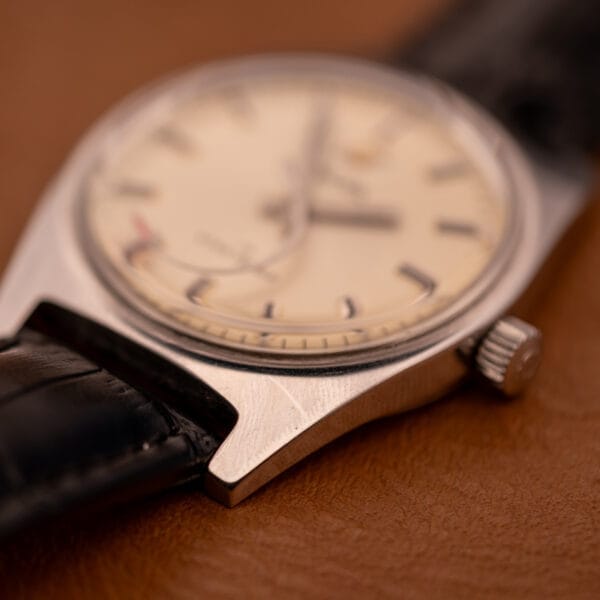 Close-up of the Enciar Ocean Peal 17 Star Jewels "Space Ship Seconds" Ref. 2334, featuring a cream dial and black leather strap on a brown surface.