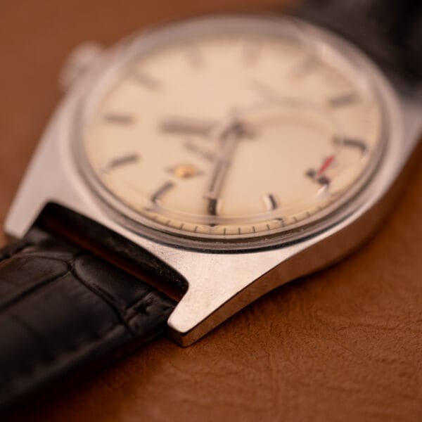 Close-up of the Enciar Ocean Peal 17 Star Jewels "Space Ship Seconds" Ref. 2334 wristwatch with a black leather strap on a brown surface, featuring star jewels on the dial.