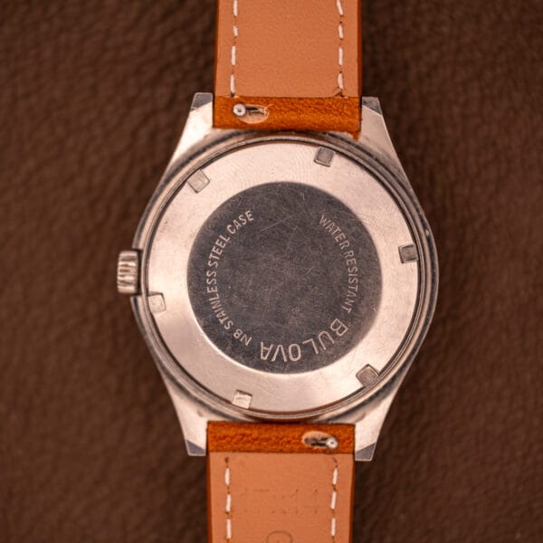 Close-up of the back of a Bulova Oceanographer Automatic 333 Feet Blue/Purple Dial Cal. 1132.10 wristwatch with a tan leather strap on a brown surface.