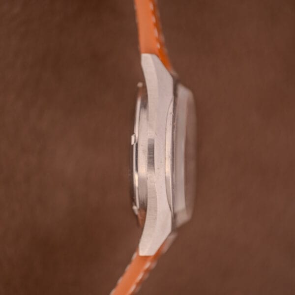 Side view of the Bulova Oceanographer Automatic 333 Feet Cal. 1132.10 with a blue/purple dial, silver case, and orange strap against a brown background.