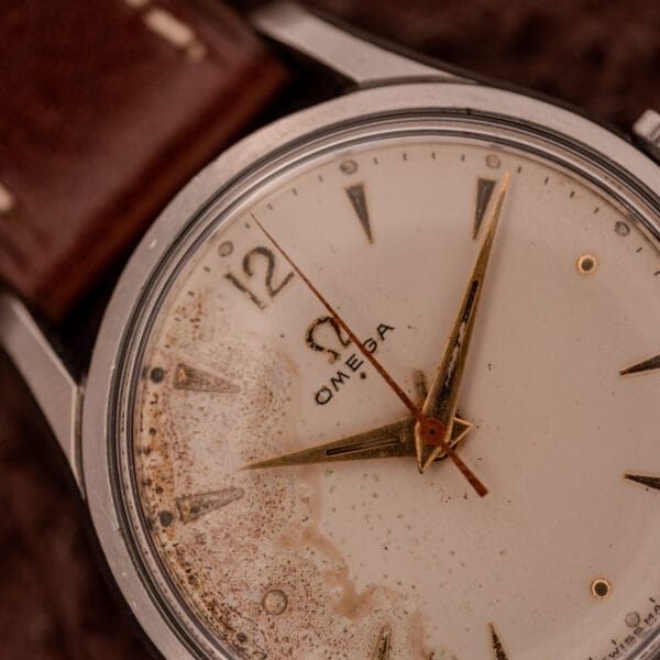Close-up of an Omega Jumbo Stainless Steel Ref. 2640 Manual Wind 283 Caliber wristwatch featuring a worn, stained dial and brown leather strap.