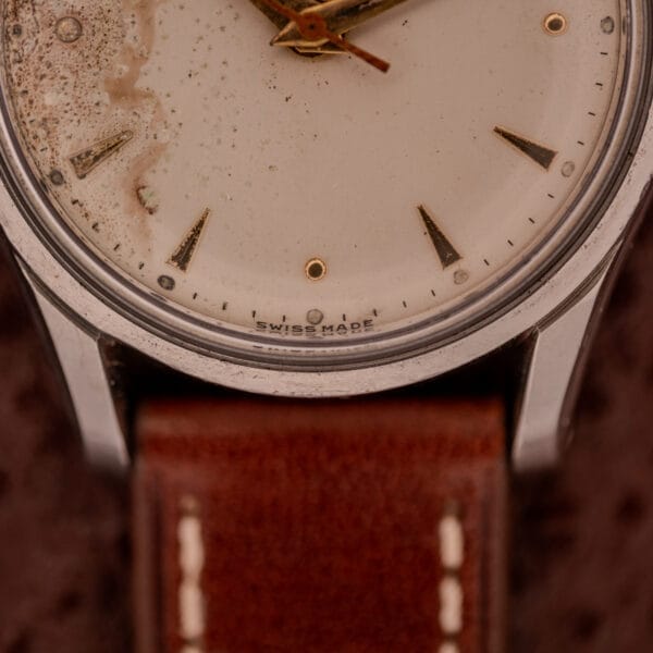 Close-up of an Omega Jumbo Stainless Steel Ref. 2640 wristwatch with a worn dial, brown leather strap, and manual wind 283 caliber movement.