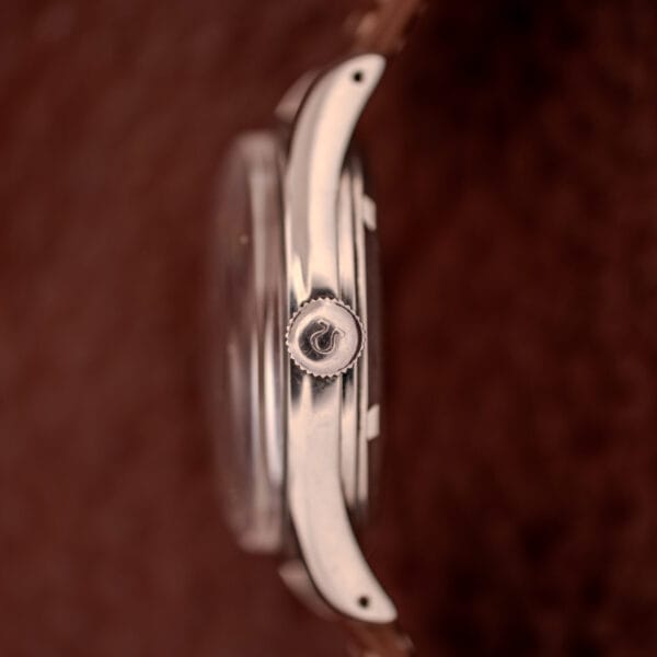 Side view of an Omega Jumbo Stainless Steel Ref. 2640 Manual Wind 283 Caliber with a silver crown, brown leather strap, and blurred brown background.