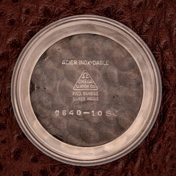 The inside case back of the Omega Jumbo Stainless Steel Ref. 2640 Manual Wind 283 Caliber features branding, reference numbers, and "Acier Inoxydable," showcasing its sturdy stainless steel build.