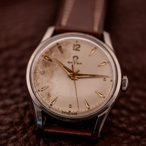An Omega Jumbo Stainless Steel Ref. 2640 wristwatch featuring a brown leather strap, patinated off-white dial, and manual wind 283 caliber movement.
