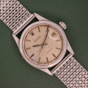 A Rolex Oysterdate Precision Ref. 6466 in stainless steel with a mesh strap displays the date as the 15th on a green background.