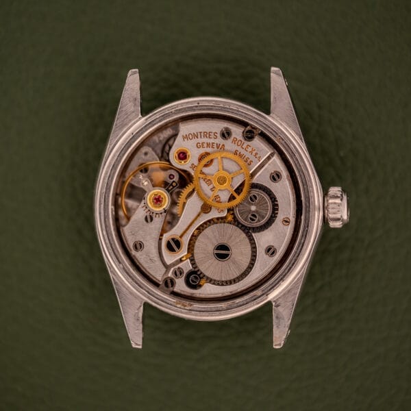 Close-up of the Rolex Oysterdate Precision Ref. 6466 in stainless steel, showcasing detailed mechanical gears and components against a green backdrop.