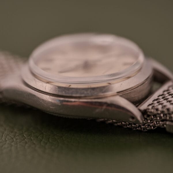 Close-up side view of the Rolex Oysterdate Precision Ref. 6466 in Stainless Steel with a metal band, displayed on a textured green surface.