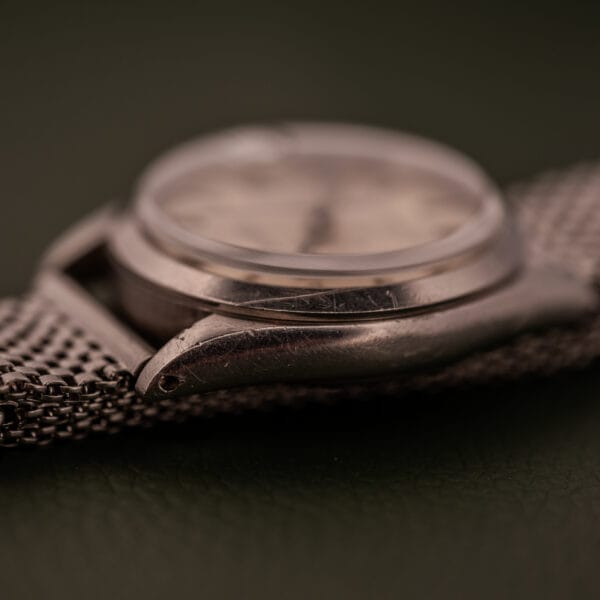 Close-up of the Rolex Oysterdate Precision Ref. 6466 in Stainless Steel with a mesh band, highlighting its detailed metal case and a softly blurred watch face.