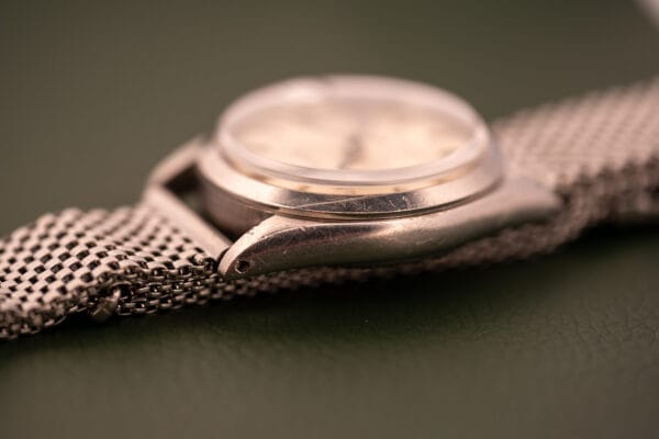 Close-up of the Rolex Oysterdate Precision Ref. 6466 in stainless steel with a mesh band, displayed on a green surface.