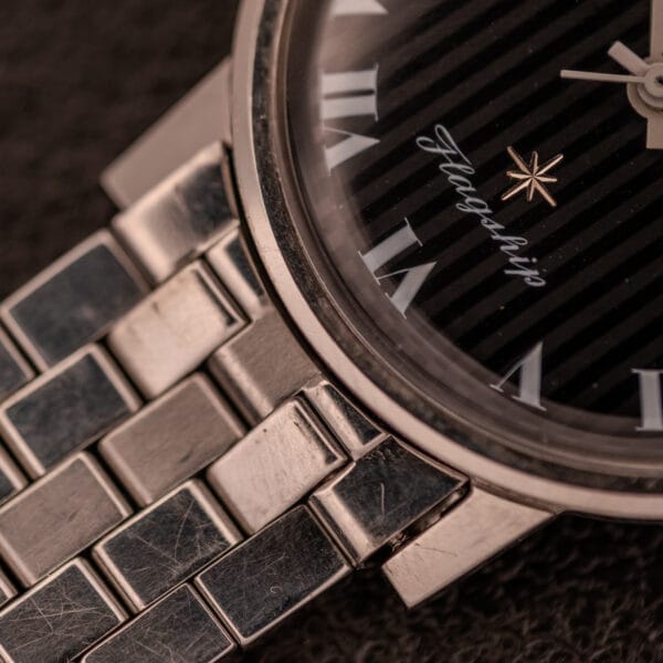 Close-up of a Longines Flagship Ref. 2821 wristwatch, featuring a black "Pinstripe" dial, diamond markers, and a metal link band.