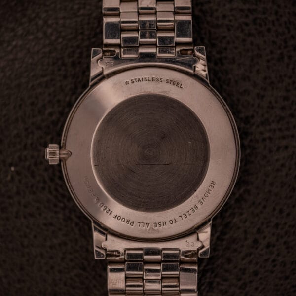 Back view of the Longines Flagship Ref. 2821 Black "Pinstripe" Dial Diamond Cal. 285, showcasing engraved text and a glimpse of its black pinstripe dial, set against a dark textured background.