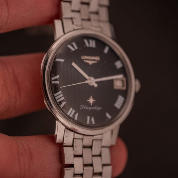 A hand holds a Longines Flagship Ref. 2821 with a black "pinstripe" dial and diamond markers, powered by Cal. 285.