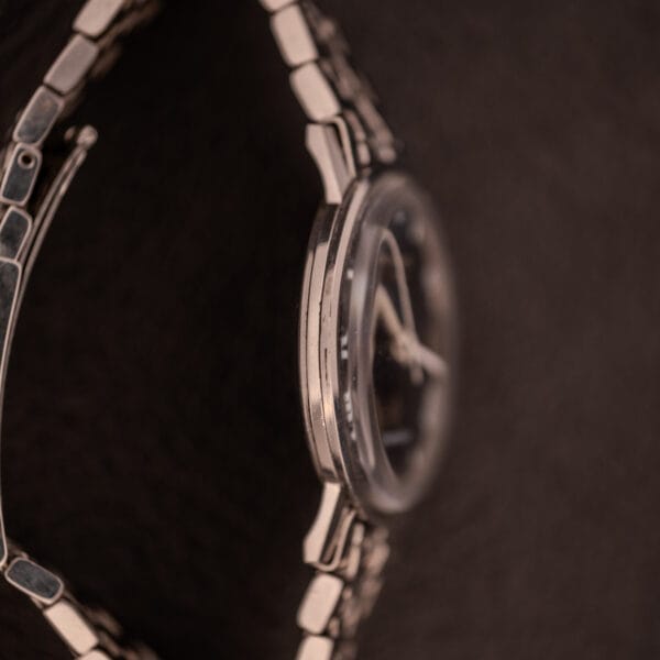 Side view of the Longines Flagship Ref. 2821 with a metal band and black pinstripe dial, Diamond Cal. 285, displayed against a dark, textured background.