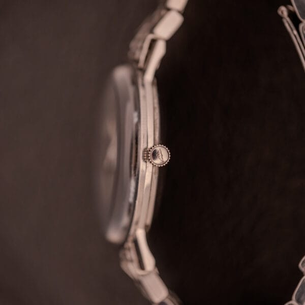 Close-up side view of a Longines Flagship Ref. 2821 Black "Pinstripe" Dial Diamond Cal. 285 wristwatch crown and case against a dark background.