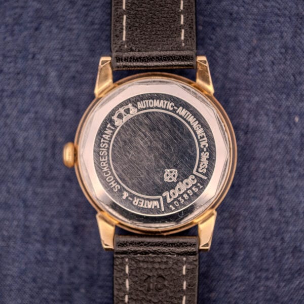 Close-up of the back of a Zodiac Glorious Automatic Tuxedo Dial Ref. 688 Cal. 1361, highlighting water resistance details and other features against a blue fabric background.