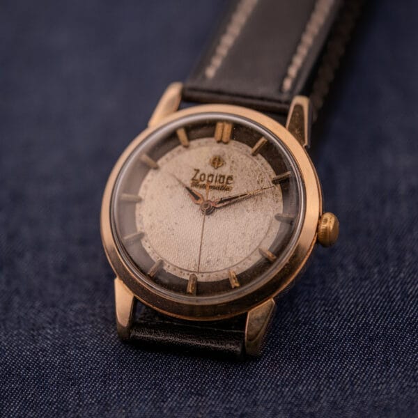The Zodiac Glorious Automatic Tuxedo Dial Ref. 688 Cal. 1361 wristwatch with a leather strap is shown resting on dark blue fabric.