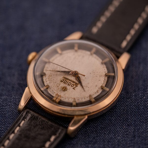 Close-up of a vintage Zodiac Glorious Automatic Tuxedo Dial Ref. 688 Cal. 1361 wristwatch with a worn dial and black leather strap on dark denim fabric.