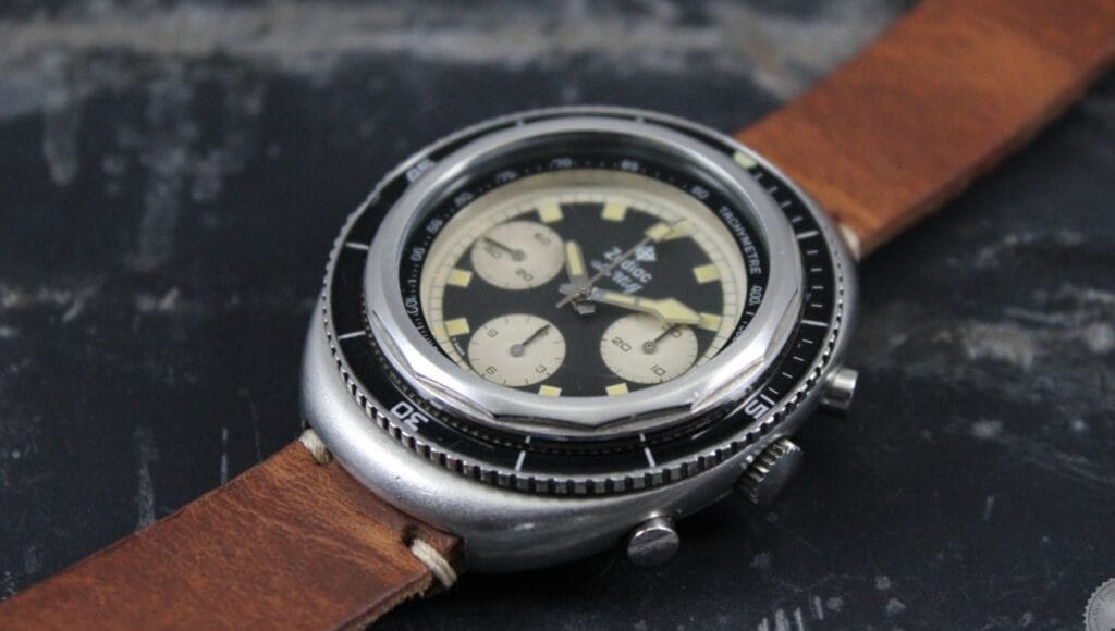 A vintage Zodiac Super Sea Wolf wristwatch with a brown leather strap and black dial, featuring three subdials, displayed on a dark surface.