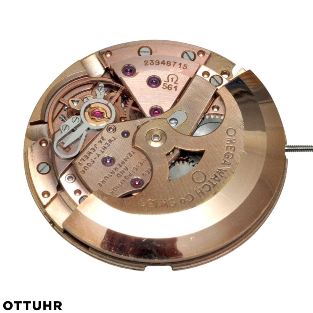 Close-up of a gold Omega 561 watch movement mechanism with visible gears, screws, and engraved markings.