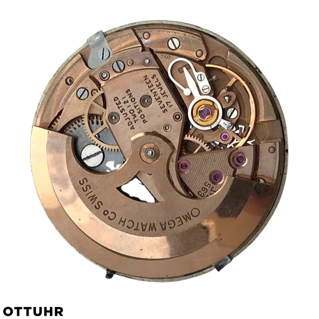 Close-up of an Omega Swiss watch movement with visible gears, engraved markings, and mechanical parts featuring the renowned Omega 563 caliber.