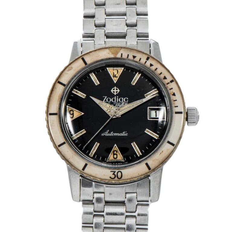 A vintage Zodiac Sea Wolf 722-946B automatic wristwatch with a black dial, silver band, and cream-colored bezel.