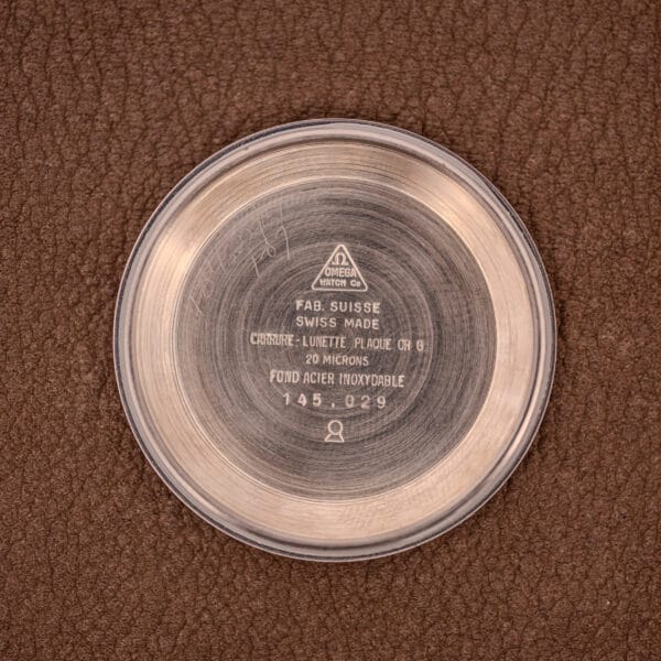 The Omega Seamaster Chronograph Ref 145.029 Cal. 861 case back with engraved markings is shown resting on a brown textured leather surface.