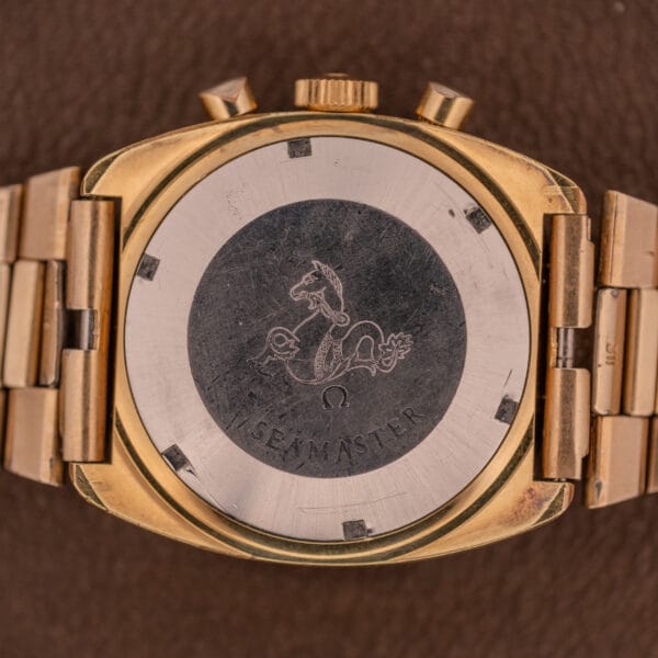 The Omega Seamaster Chronograph Ref 145.029 Cal. 861 features a gold case back with the engraved seahorse logo on a brown background, showcasing the precision of its renowned Cal. 861 movement.