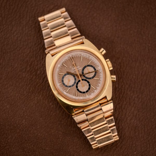 An Omega Seamaster Chronograph Ref 145.029 with a brown dial, chronograph subdials, and Cal. 861 movement is displayed on a brown textured surface.