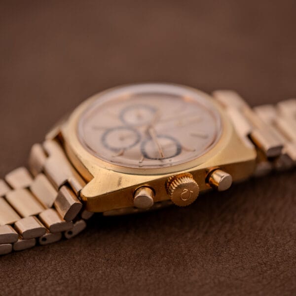 Close-up of an Omega Seamaster Chronograph Ref 145.029 featuring a Cal. 861 movement and metal band, displayed on a brown textured surface.