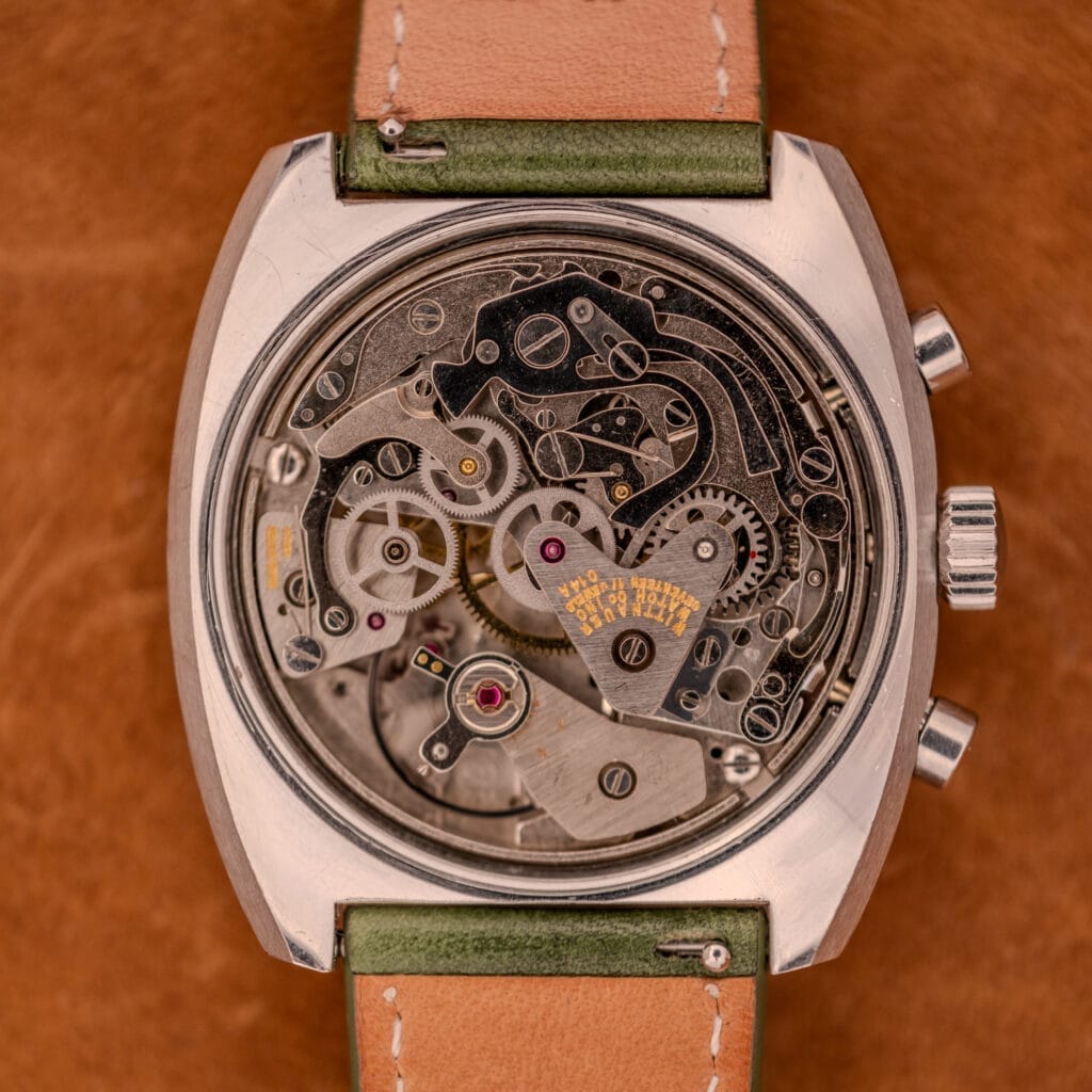 Close-up of the Wittnauer Professional Chrono-Date 8031 Blue Reverse Panda Dial, highlighting its mechanical movement with visible gears and screws, paired with a tan leather strap against a brown background.