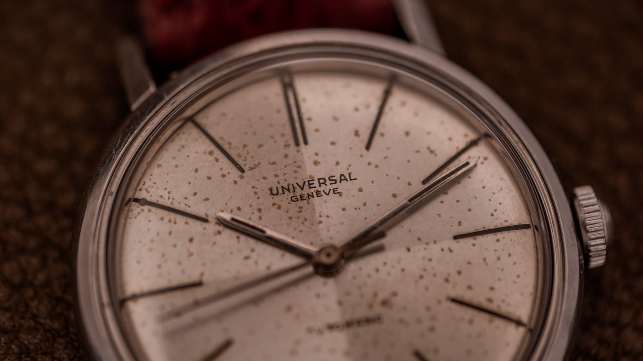 Close-up of a vintage Universal Genève wristwatch with a speckled, aged dial and silver hour markers, showcasing the timeless elegance found in classic Universal Genève watches.