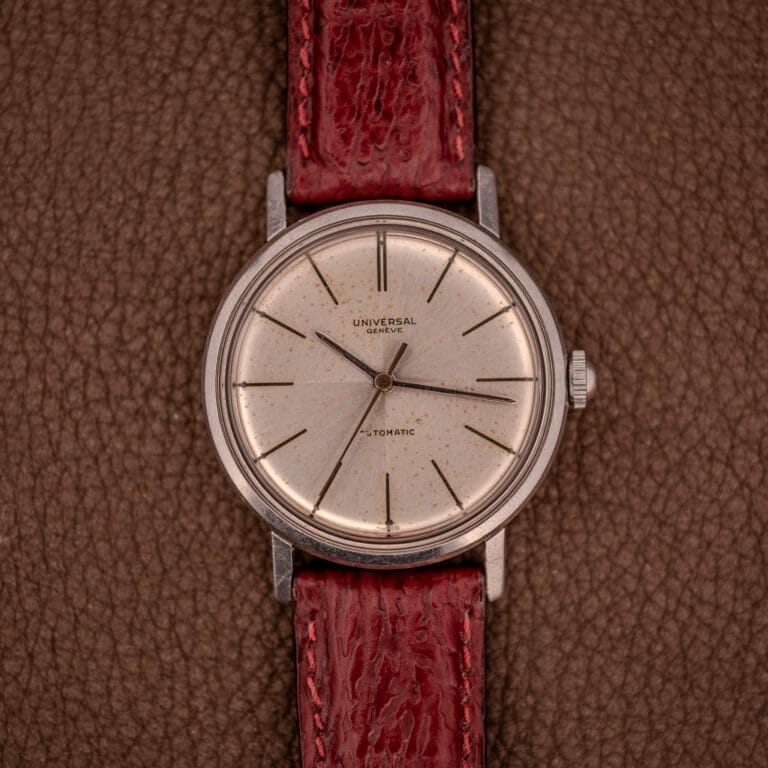 A Universal Geneve Polerouter 20375-4 "Incognito Dial" Micro Rotor Cal. 215 with a red leather strap rests on a brown textured surface.