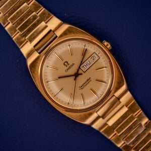 Omega Seamaster Automatic Day/Date 166.0216 Cal. 1022 watch in gold, shown on a blue background.