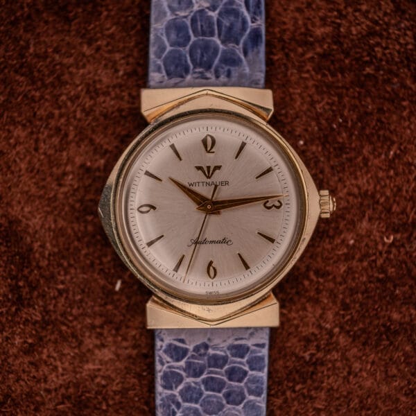 A Wittnauer Automatic Ref. 2598-1 Hooded Lugs Cal. 11SR with a blue textured strap is displayed on a brown fabric background.