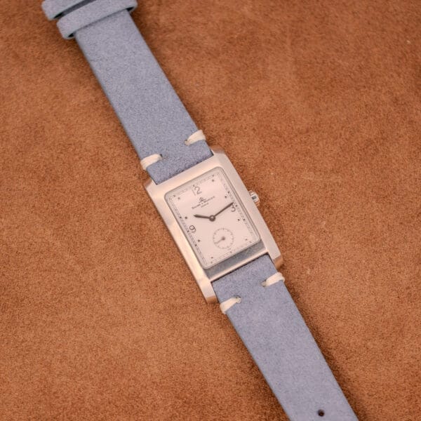 The Baume Mercier Hampton Large MV05063 features a white dial, quartz movement, and a stylish leather strap.