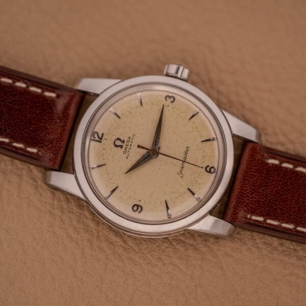 Omega Automatic Seamaster Ref. 2846-2848 in stainless steel with Cal. 500 movement, featuring a cream dial and brown leather strap, elegantly displayed on a tan leather surface.